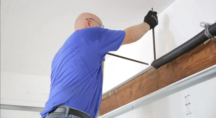 Worker performing garage door spring service