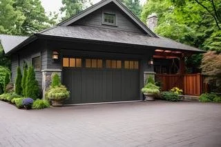 Luxreen garage door - two-car garage with a windowed door, surrounded by lush green bushes and trees, with a paved driveway in front.