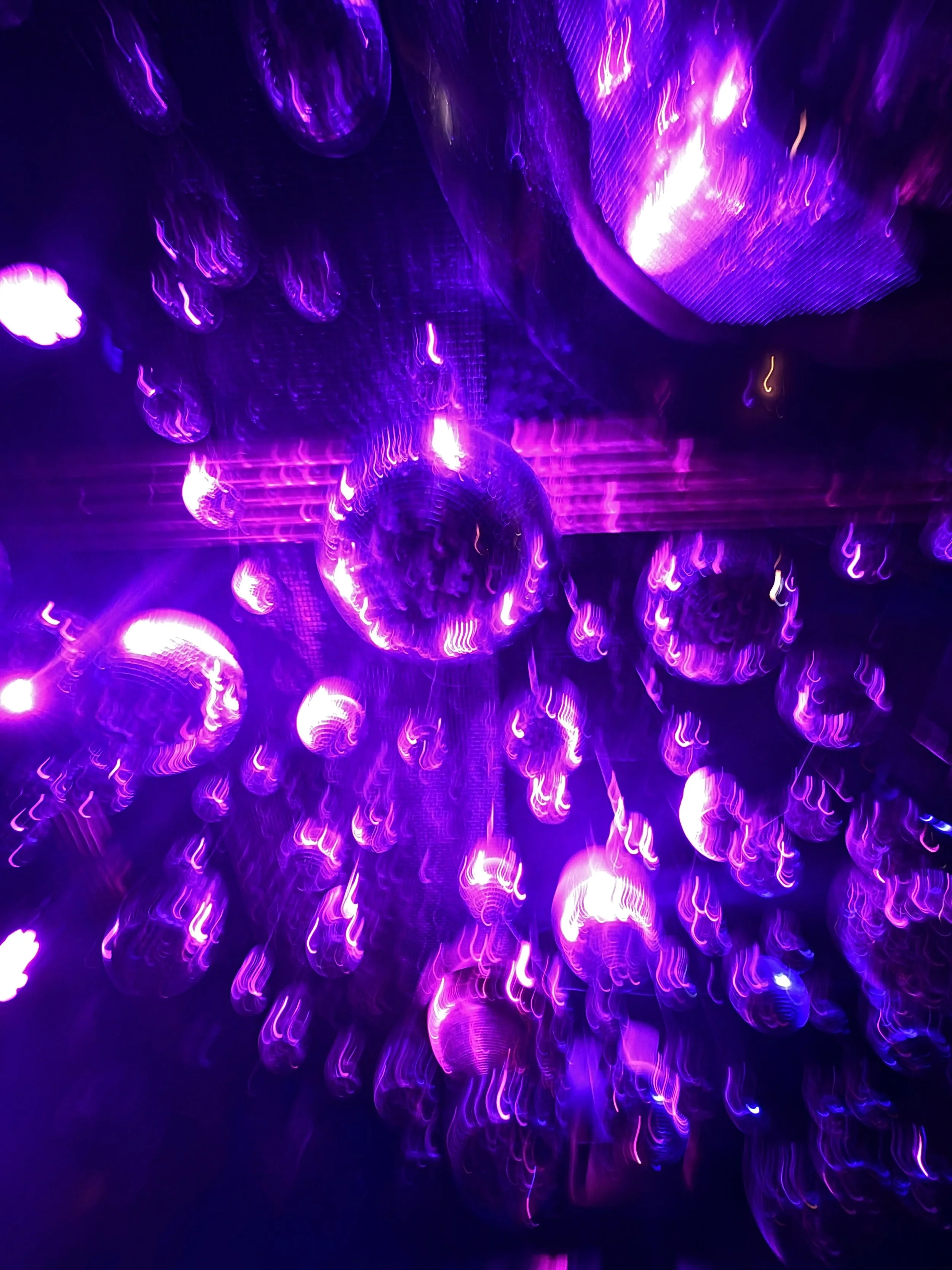 Purple and pink glowing mirrorballs, creating abstract reflective patterns