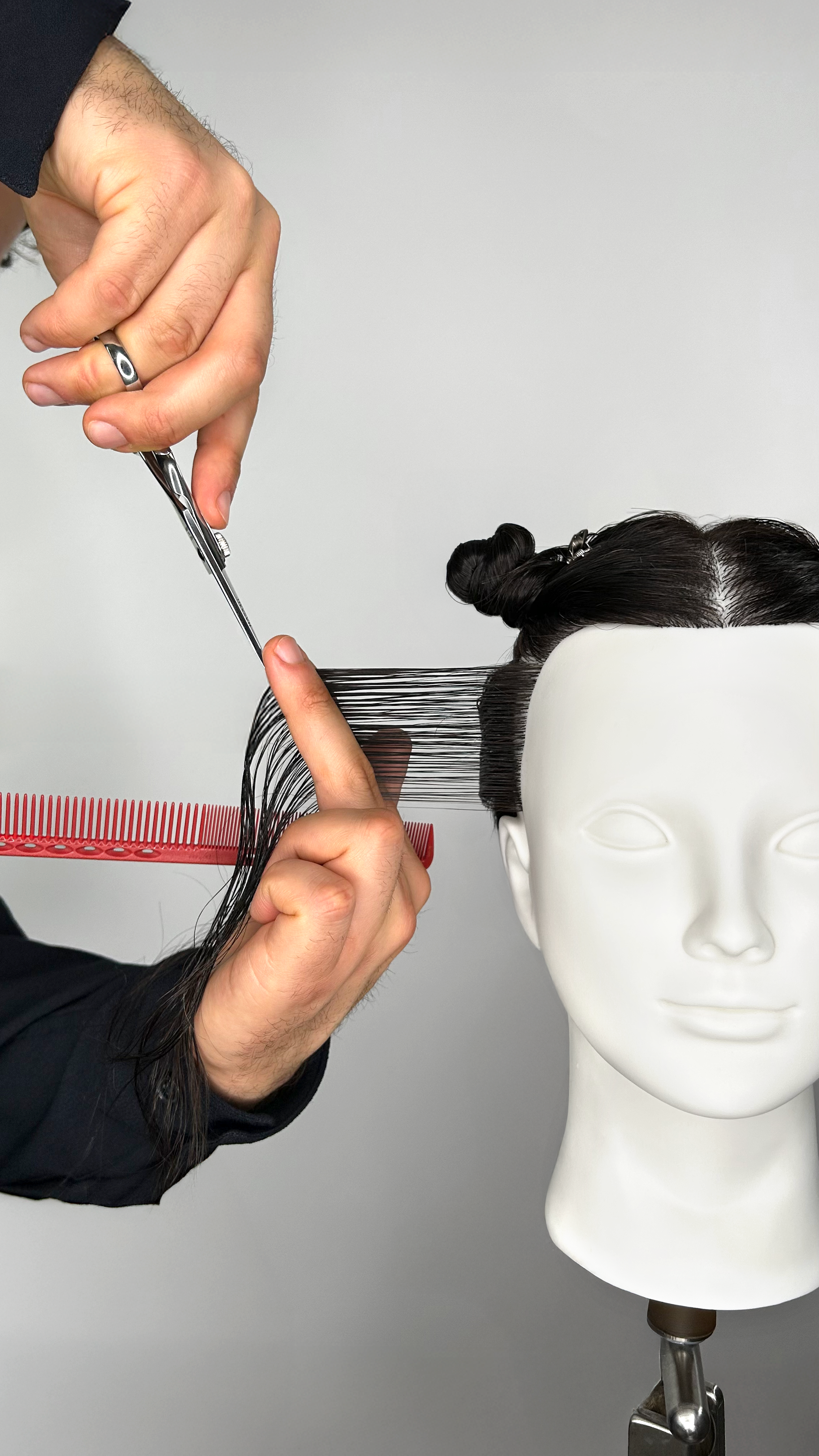 Haarschneide-Trainer zeigt Haarschnitt-Technik am Übungskopf während eines Online Haarschneide-Trainings