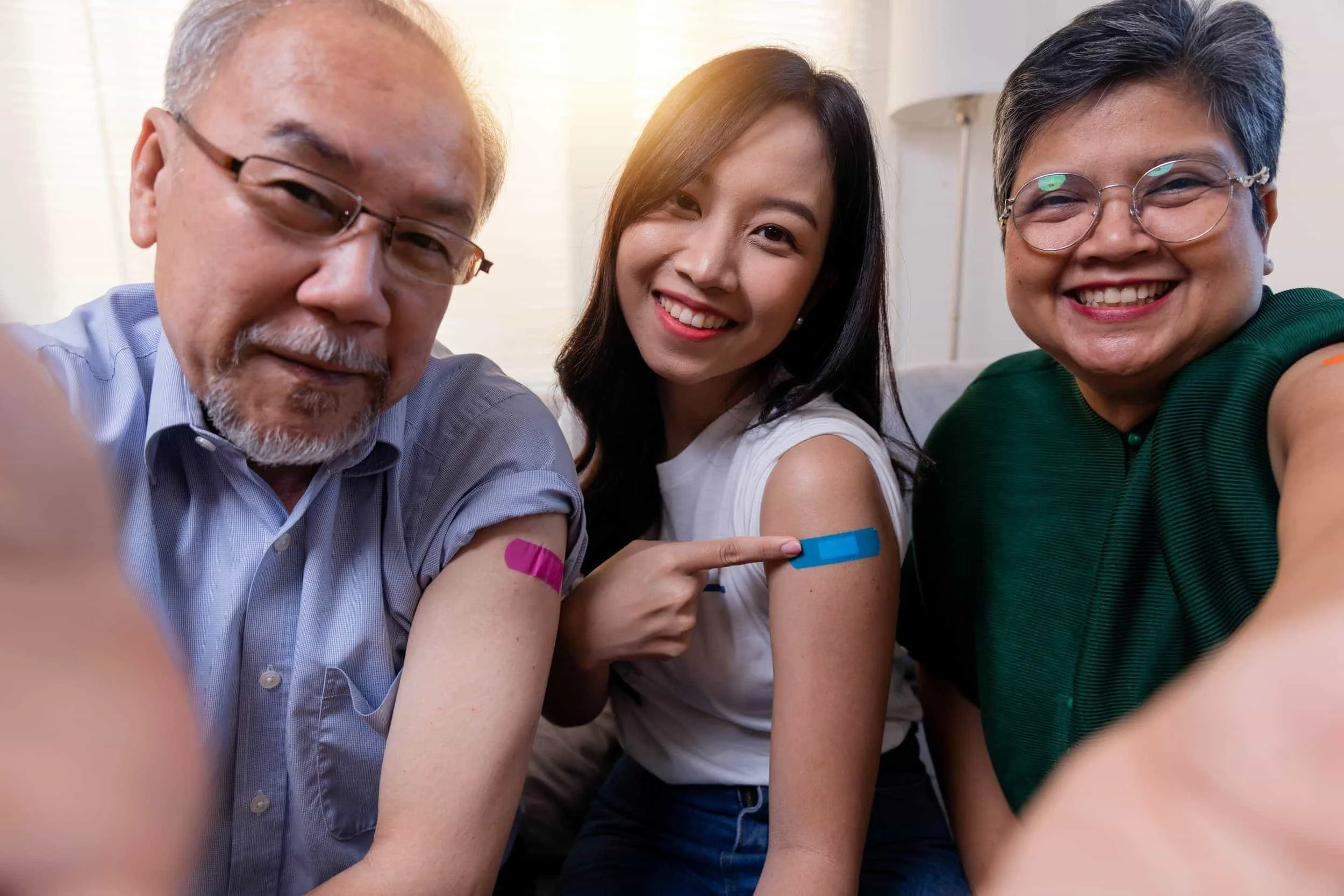 A family smiling with bandaids on their arms.