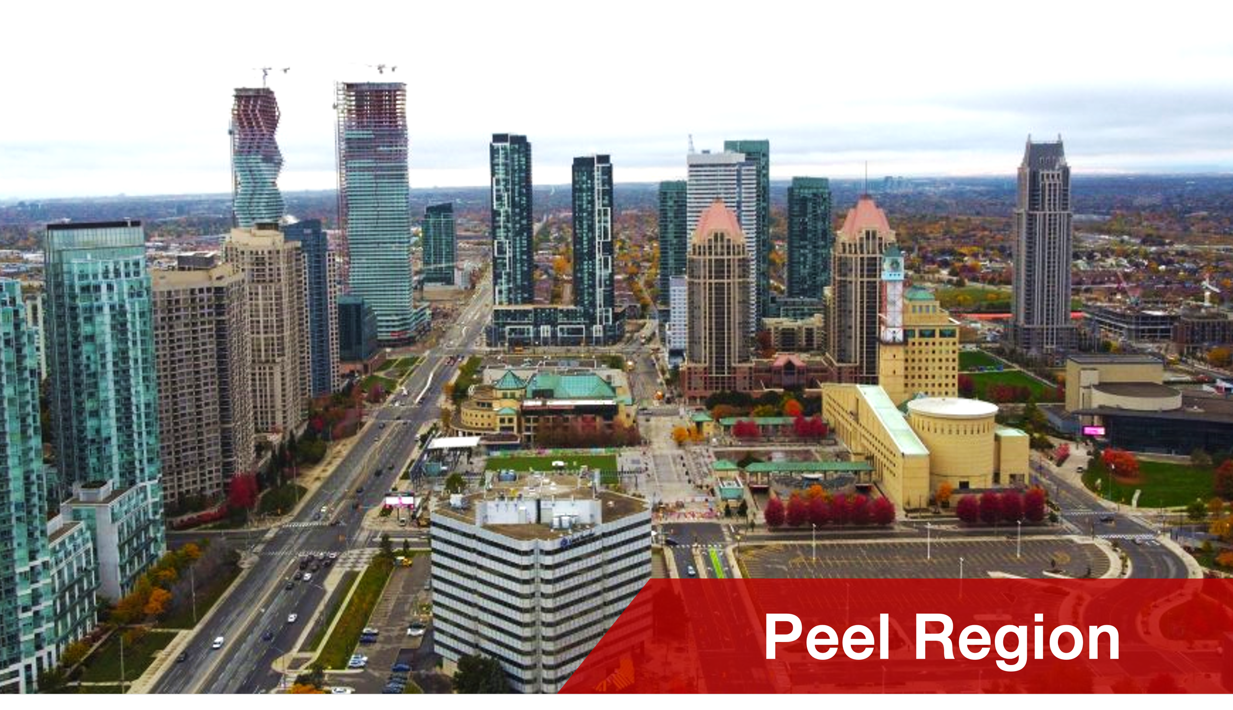 Cityscape of downtown Brampton with tall buildings, roads, and trees with fall foliage, with the text 'Peel Region' in a red banner at the bottom.