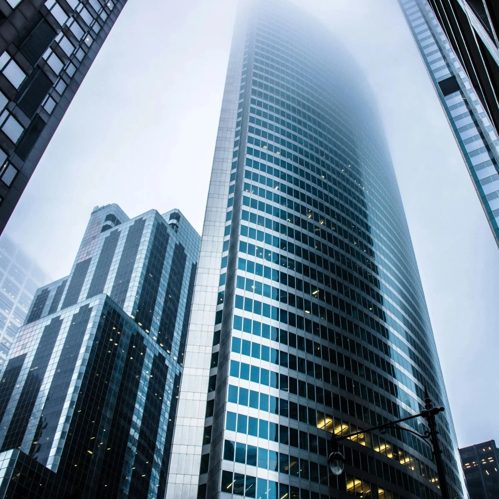 Tall modern glass skyscraper in foggy cityscape