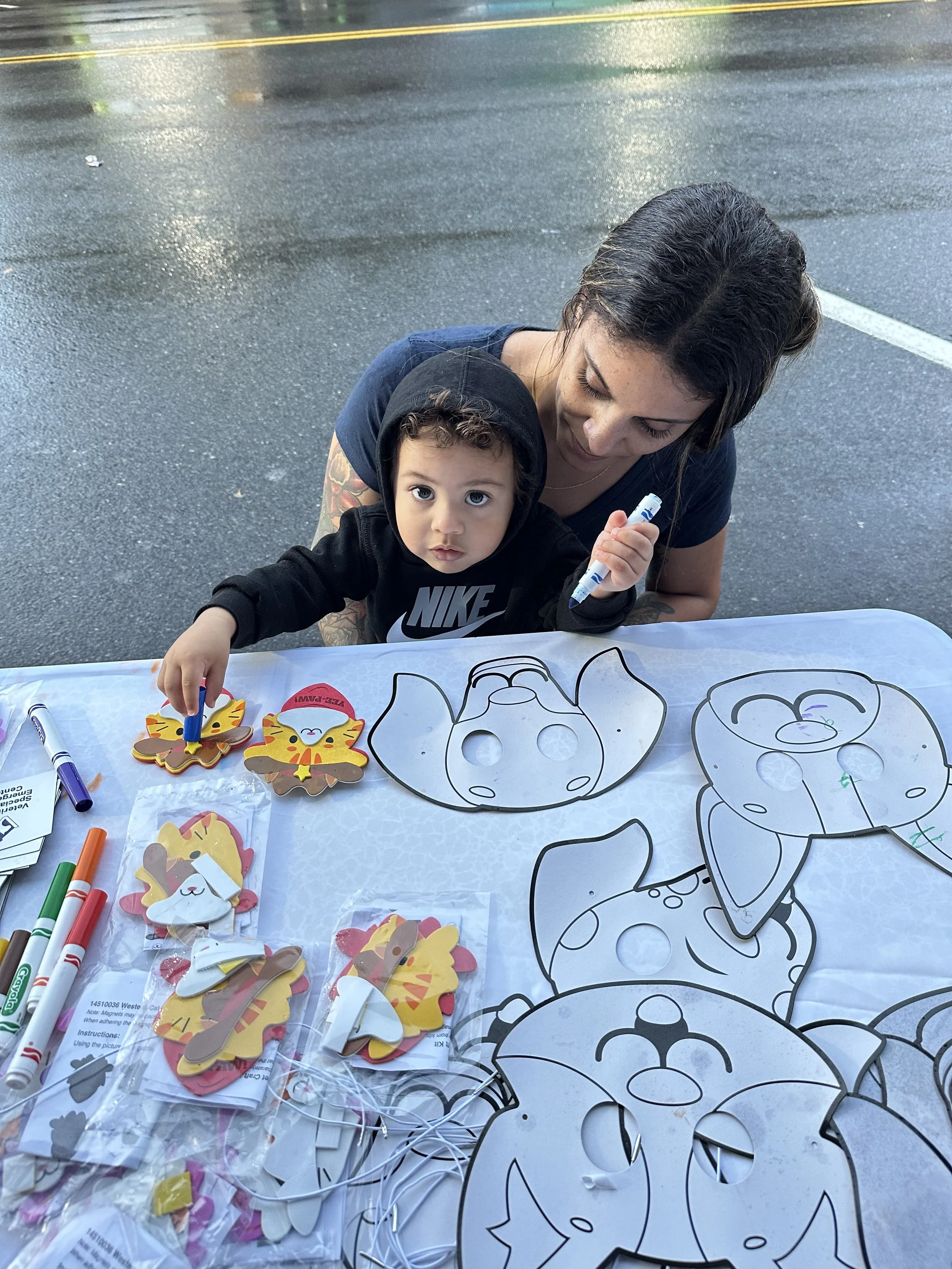 A mom and child coloring dog masks at a street fair event