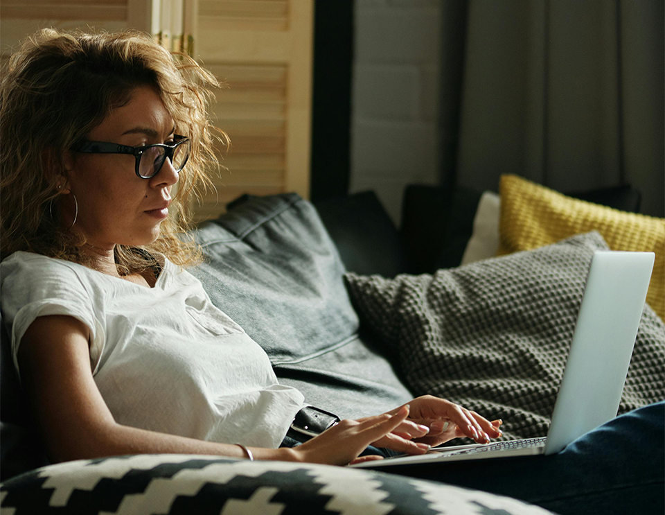 woman sitting on a couch writing on her laptop