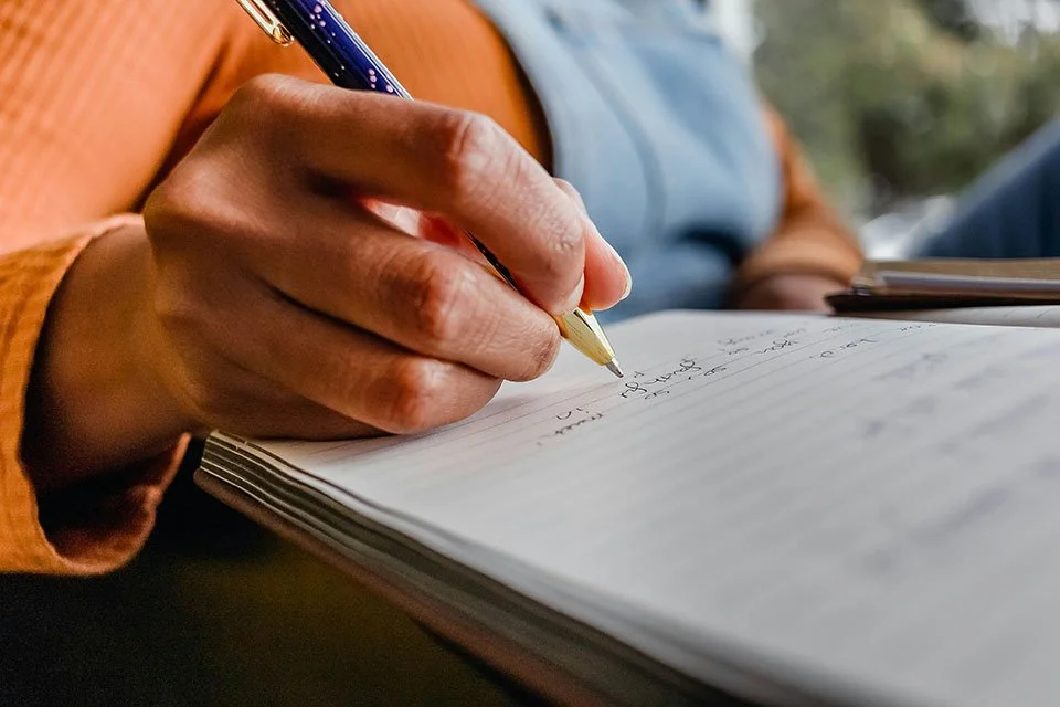 Woman writing in a notebook, jotting down her memories