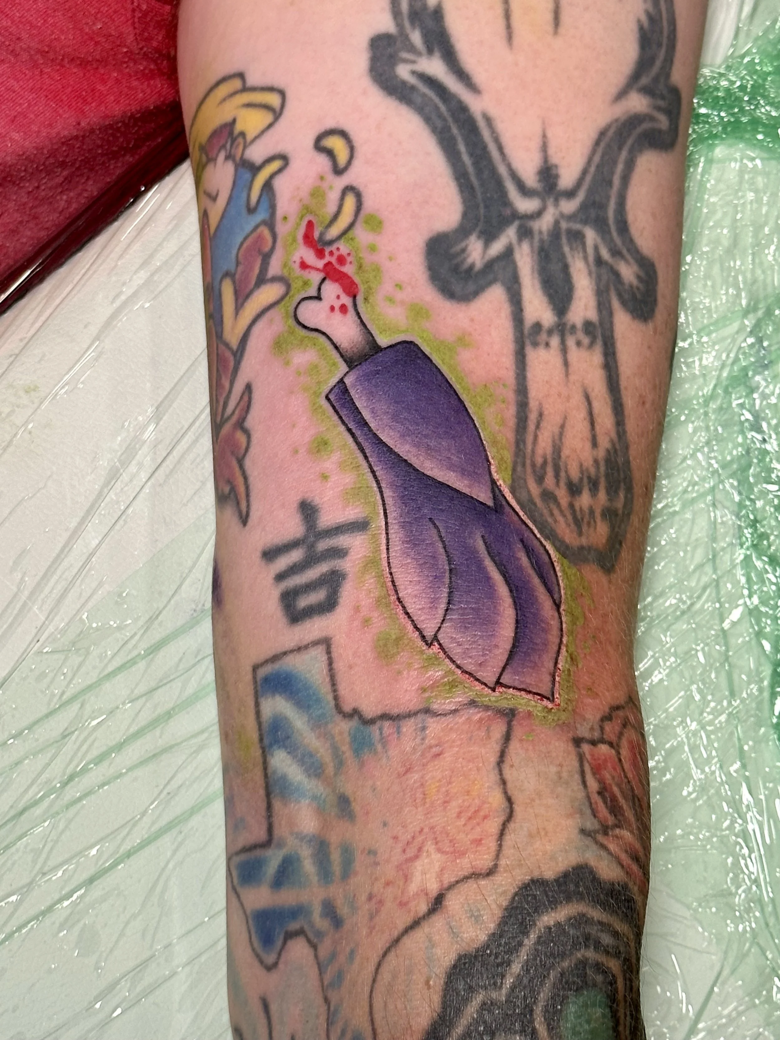 Tattoo of a lit cigarette with purple smoke and red cherry on the end, surrounded by green splashes.