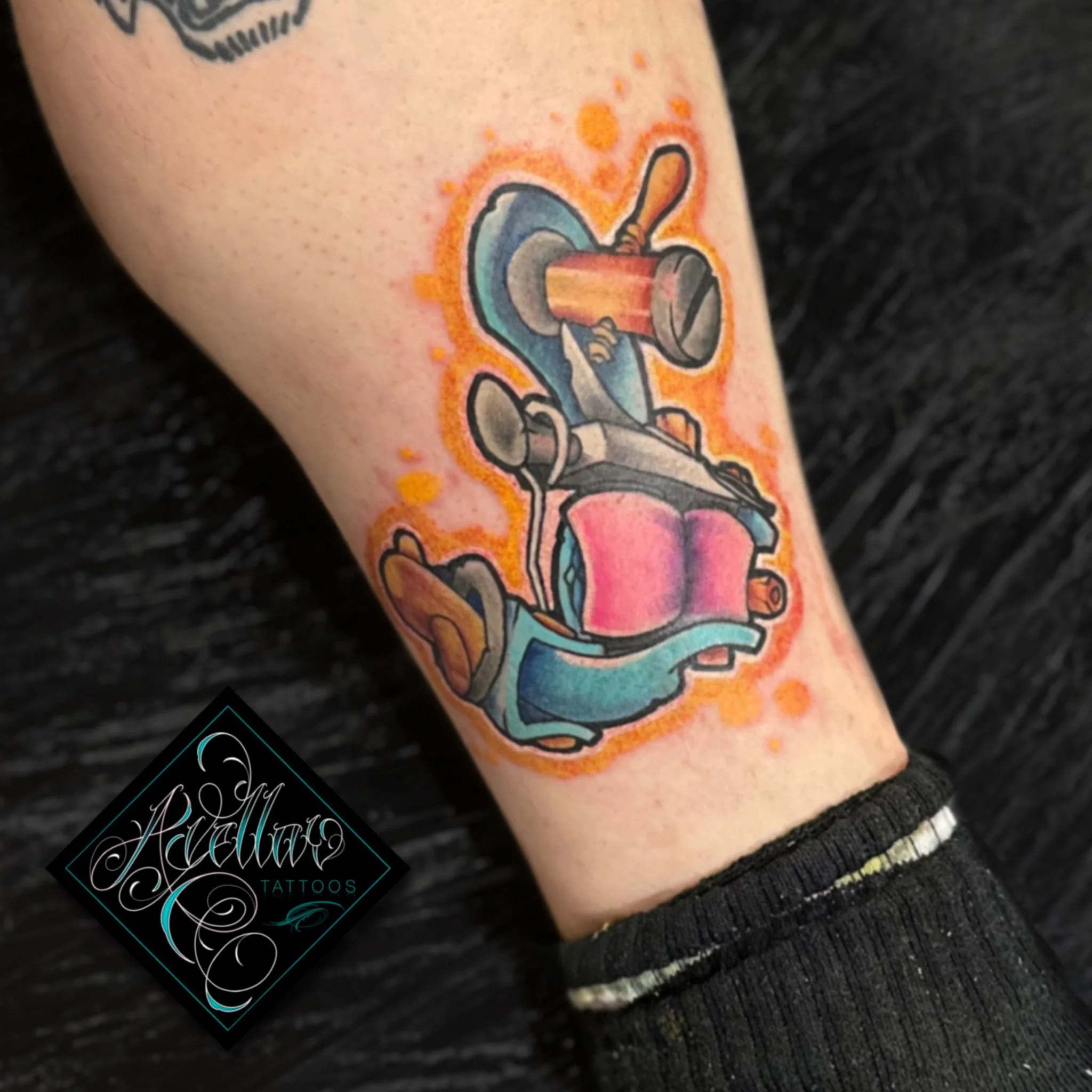 Colorful tattoo of a scooter with a soda can on top, surrounded by orange splashes and a neon-like glow, on a person's arm.