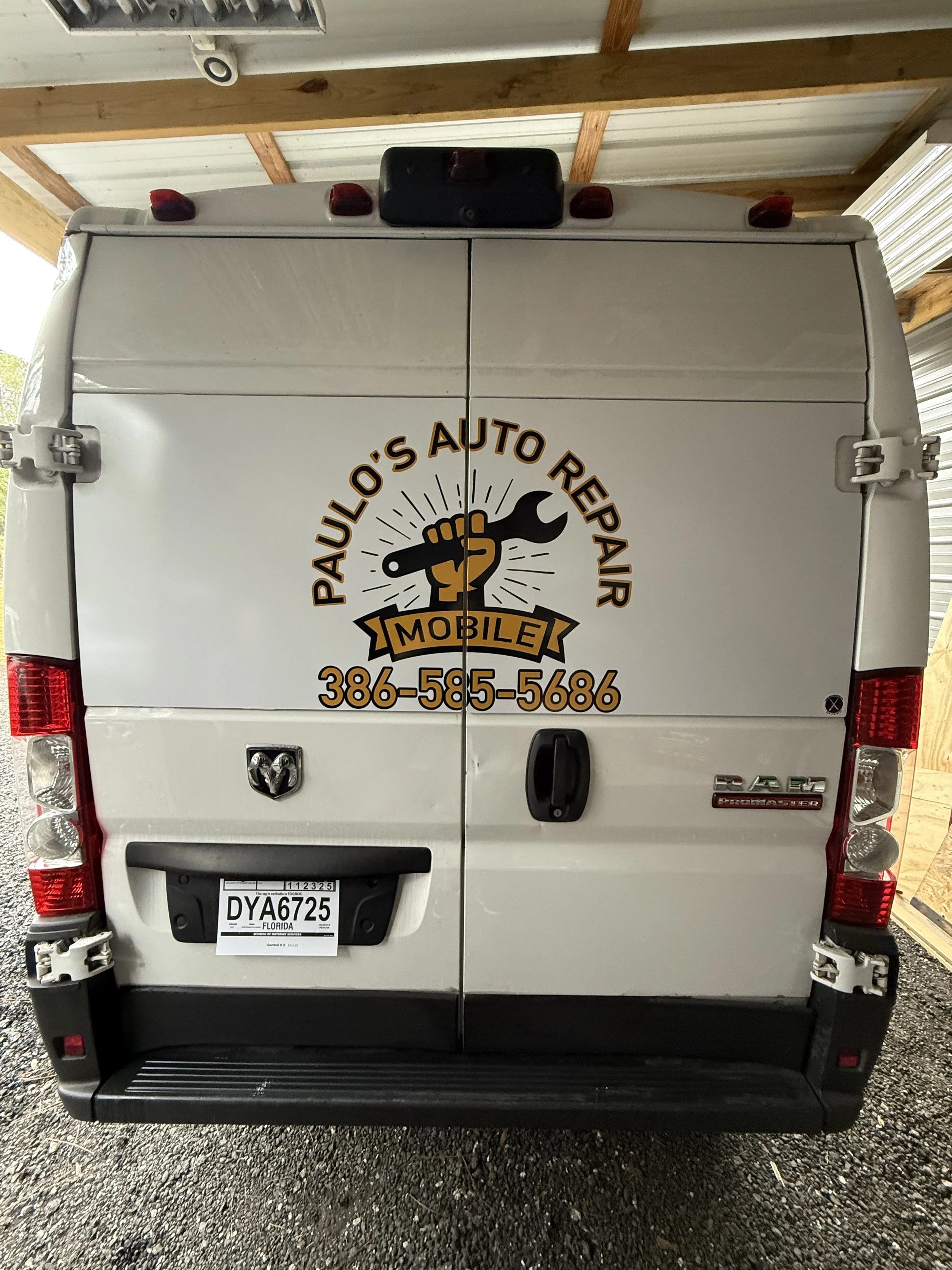 Back of a white auto repair service van with vinyl graphic logo 'Paul O's Auto Repair' and a hand holding a wrench, with the phone number 386-585-5686.