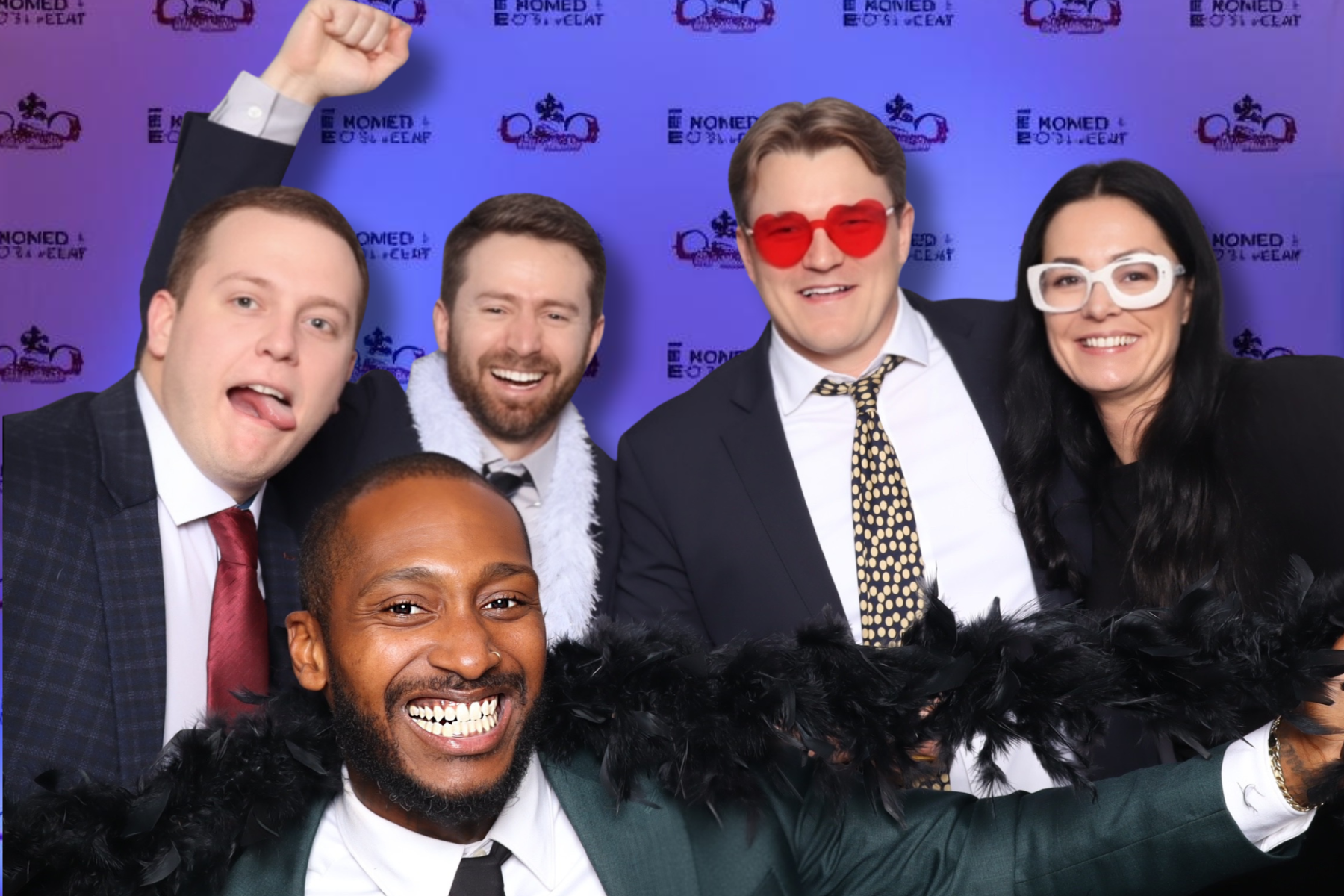 Two women taking a photo with a photo booth, smiling and making peace signs, with a white umbrella overhead and potted plants in the background.