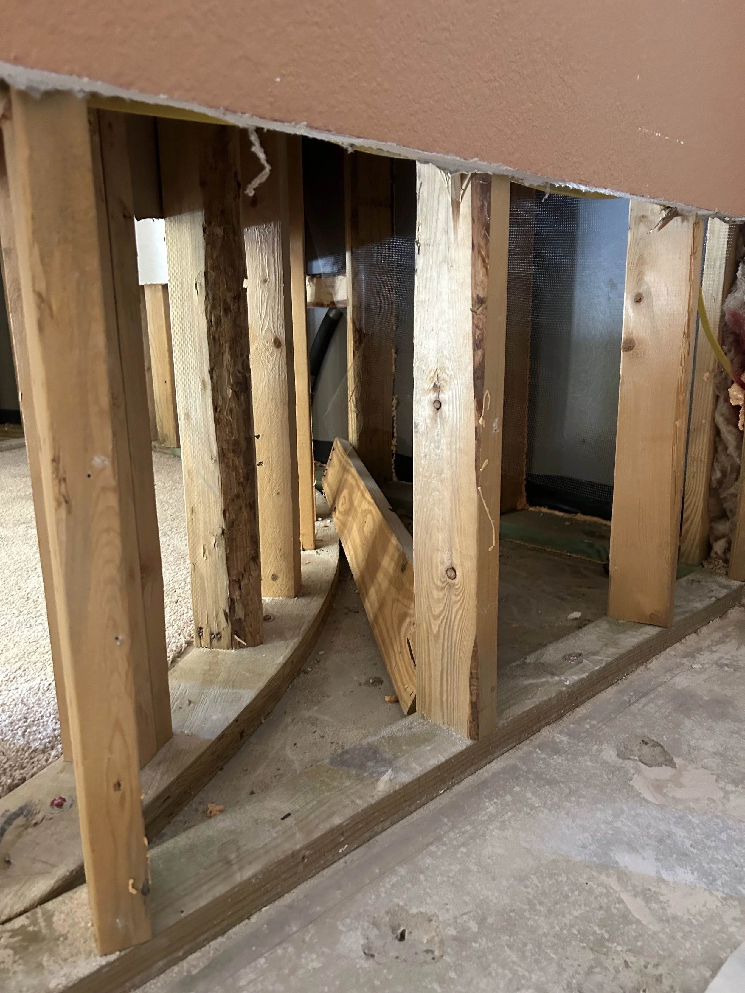 Interior wall with missing drywall exposing wooden studs and structural elements