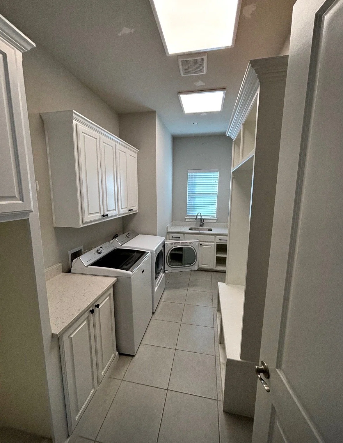 Laundry room with white cabinets, washer, dryer, and utility sink