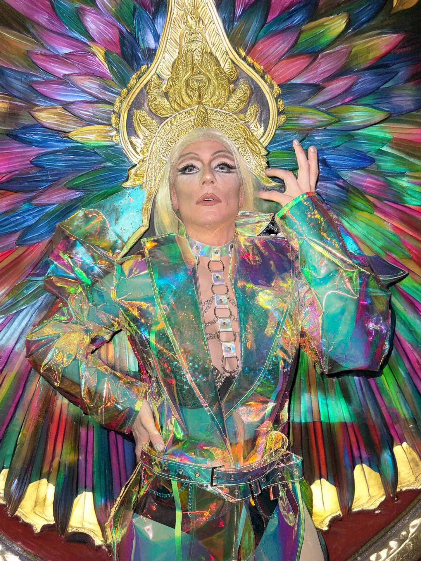Nahaufnahme von Liz Queera in einem extravaganten Show-Kostüm mit goldenem Kopfschmuck und holografischer Jacke.