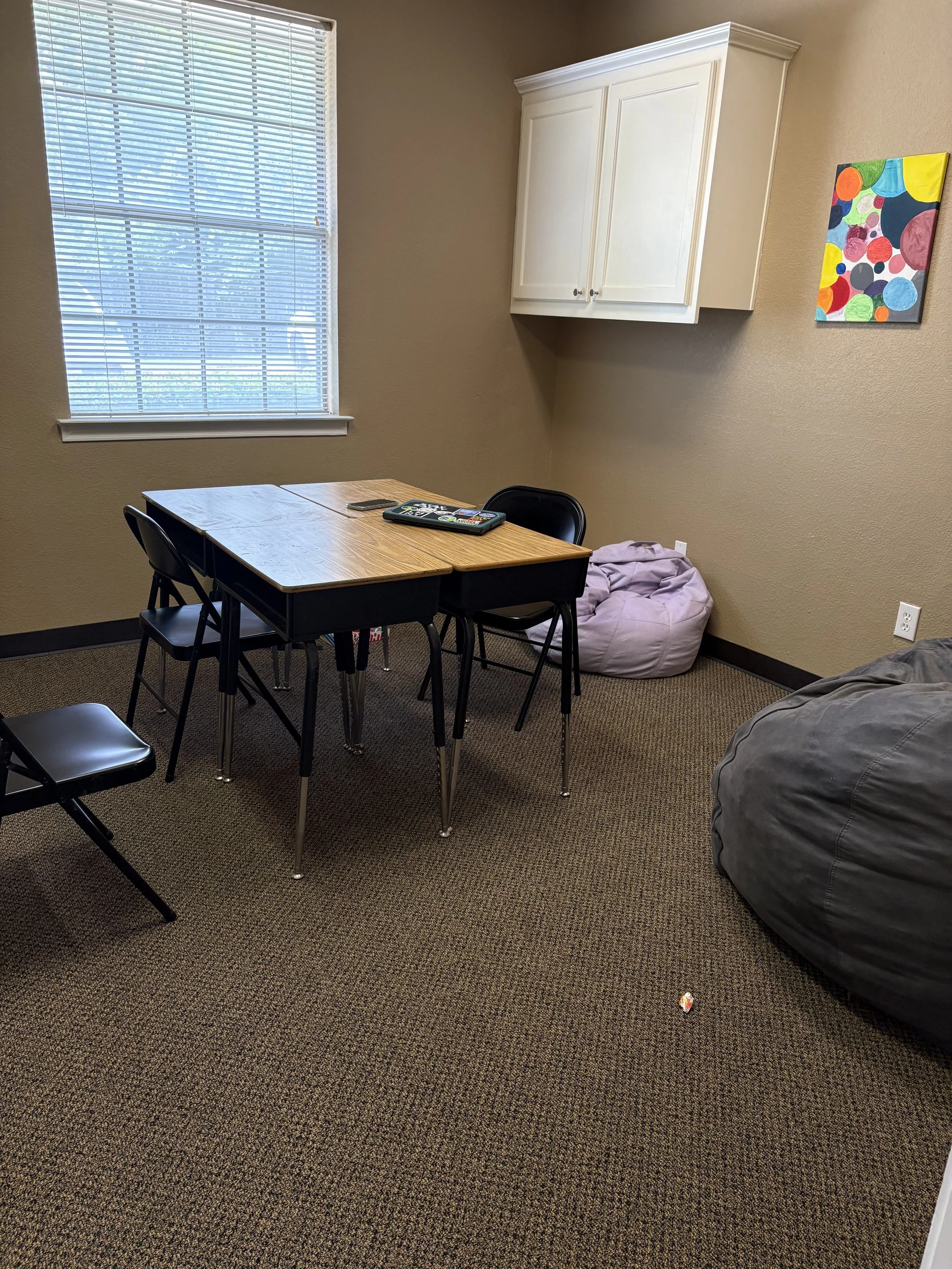 Picture of the social skills group room, has a group of 4 desks and some beanbags