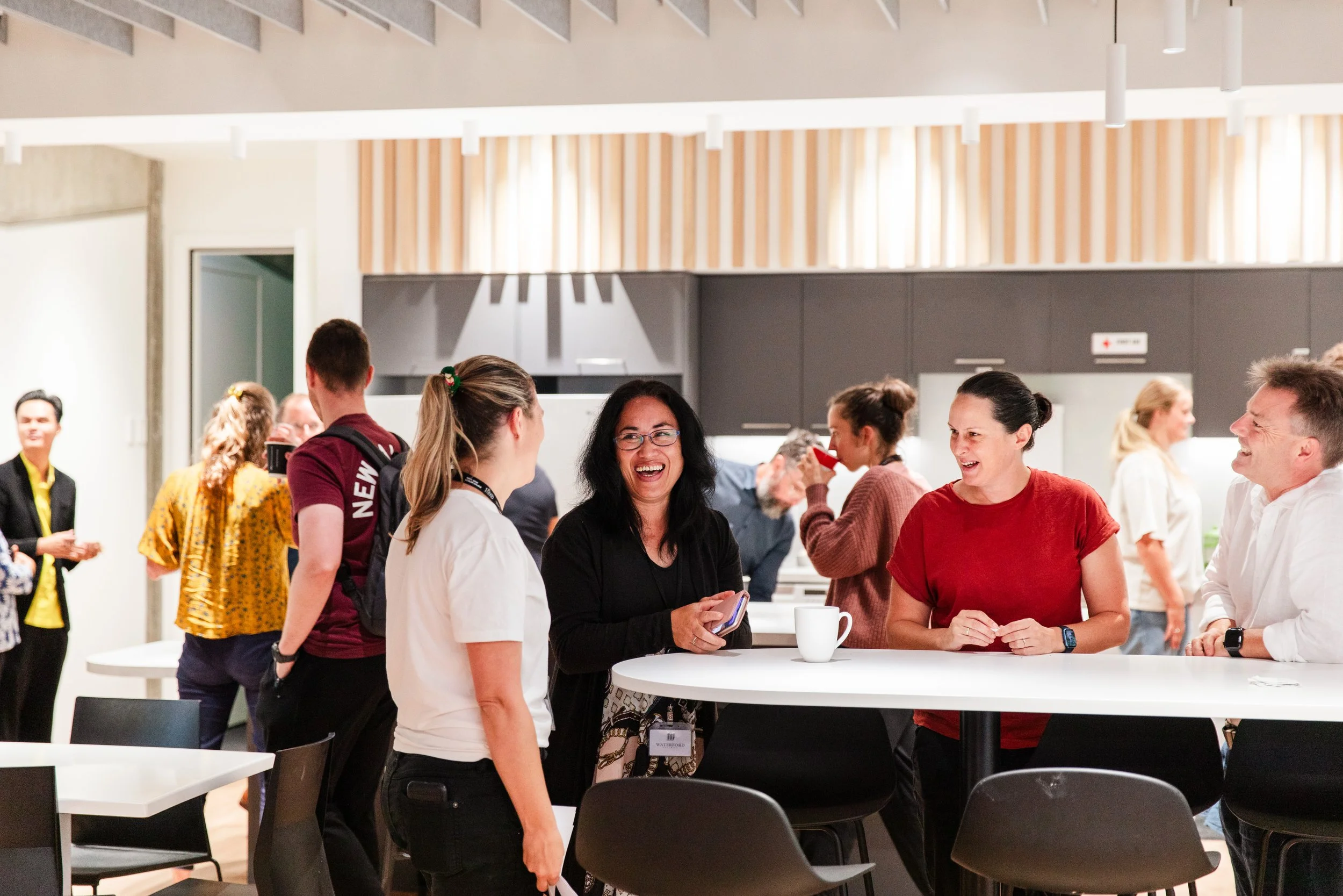 Group of people socializing and laughing at a modern indoor event space.