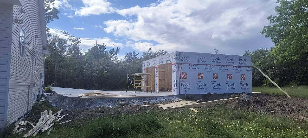 Under construction house with exterior walls covered in Tyvek HomeWrap and a concrete foundation.