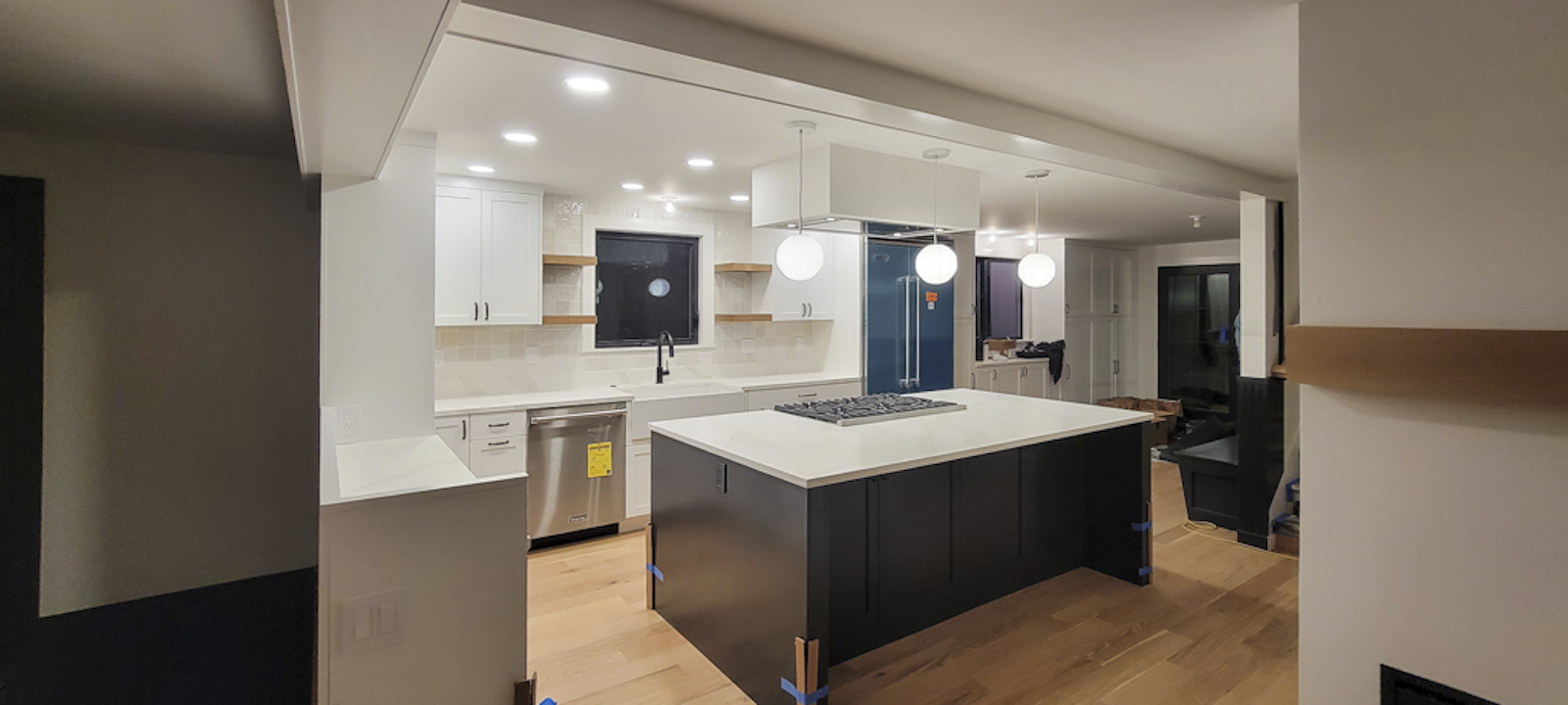 Modern kitchen with white cabinets, an island with a black base, a white countertop, pendant lights, and stainless steel appliances.