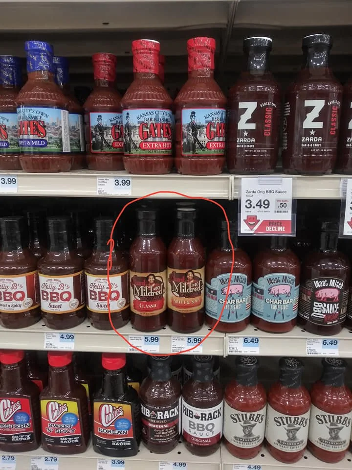 Shelf of barbecue sauces, including multiple bottles of 'Mildeeds', with red caps and labels, circled in red.