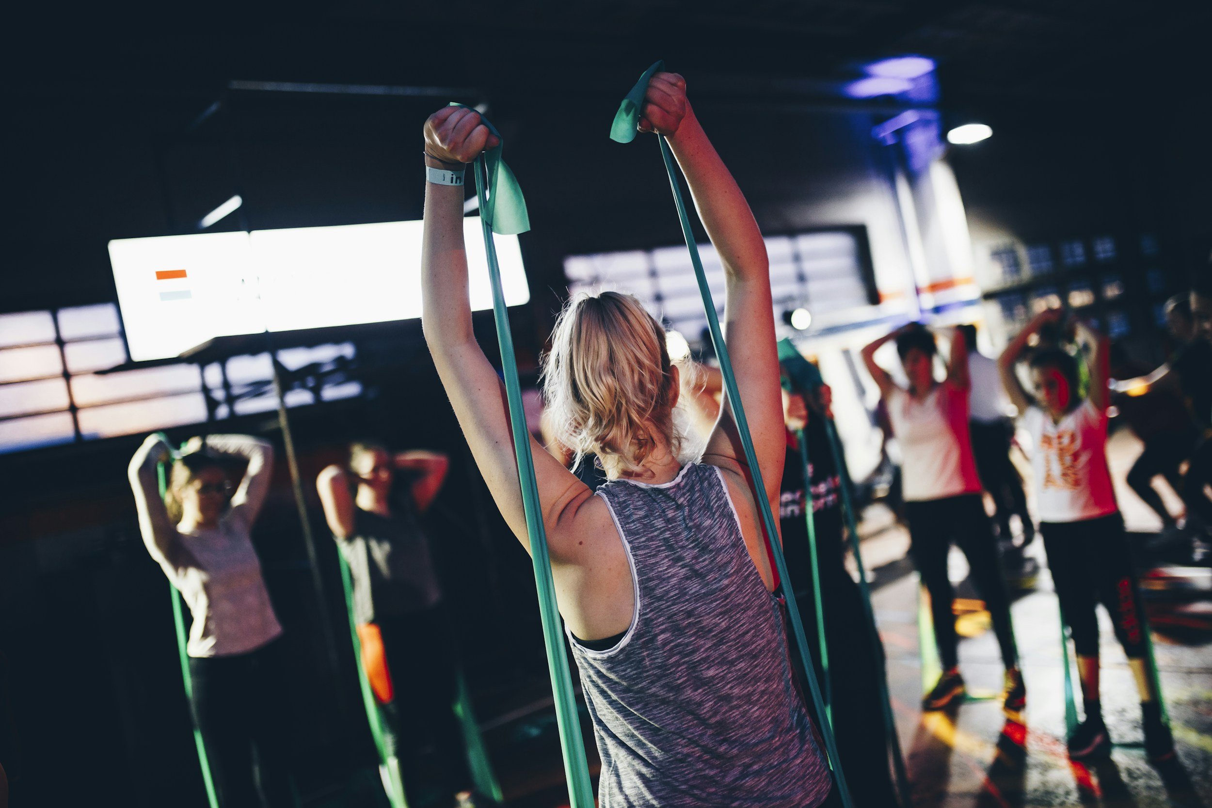 Women participating in a fitness class with resistance bands in a gym.