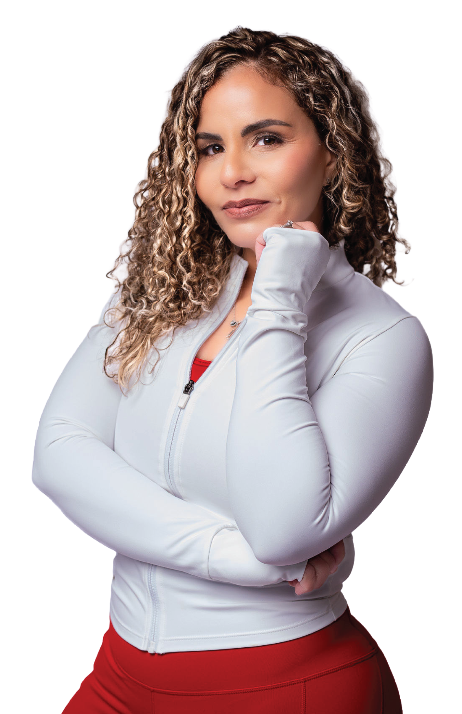A woman with curly hair wearing a white athletic jacket and red sports pants, posing with her hand near her chin and smiling.