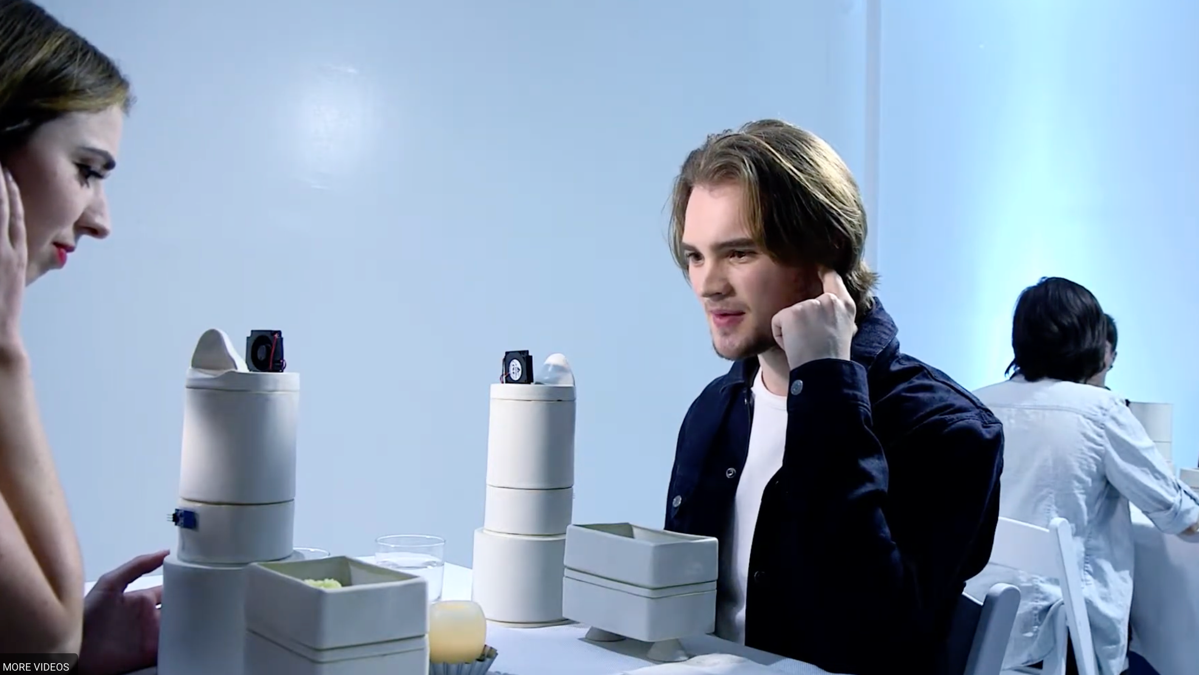 People playing chess with intelligent chess robots on a white table in a bright, modern room.