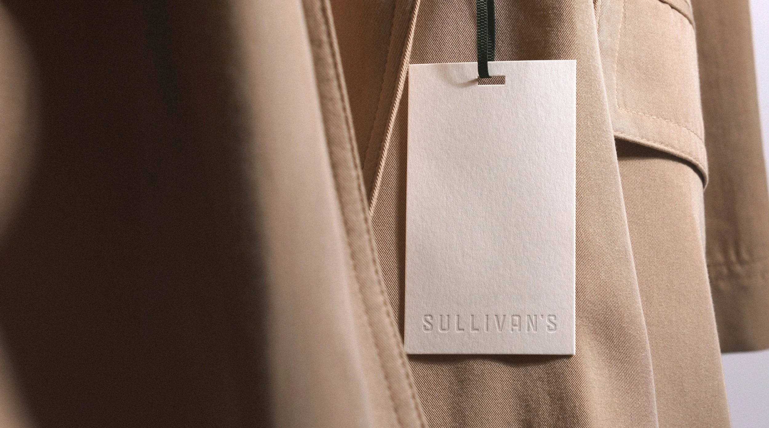 Swing tag for Sullivan's shown on a beige coat