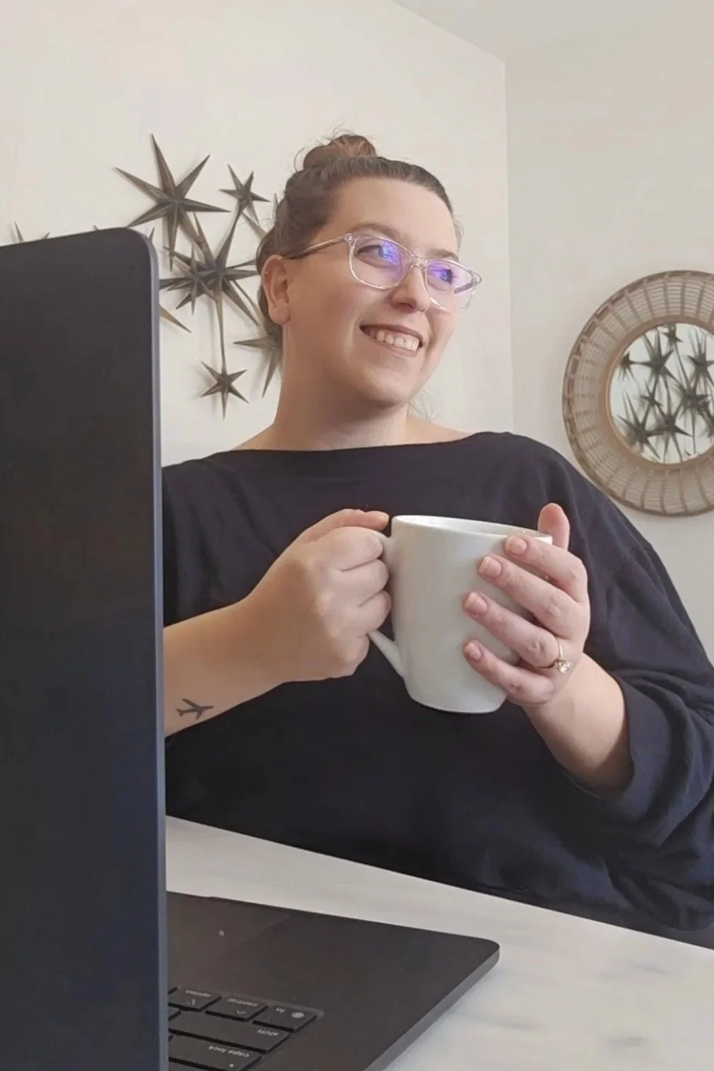 Rachel Kellam holding a mug in front of a computer