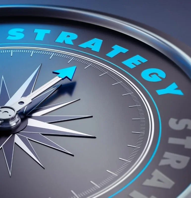 Close-up of a compass with the word 'STRATEGY' written around the outer edge and an arrow pointing towards it.