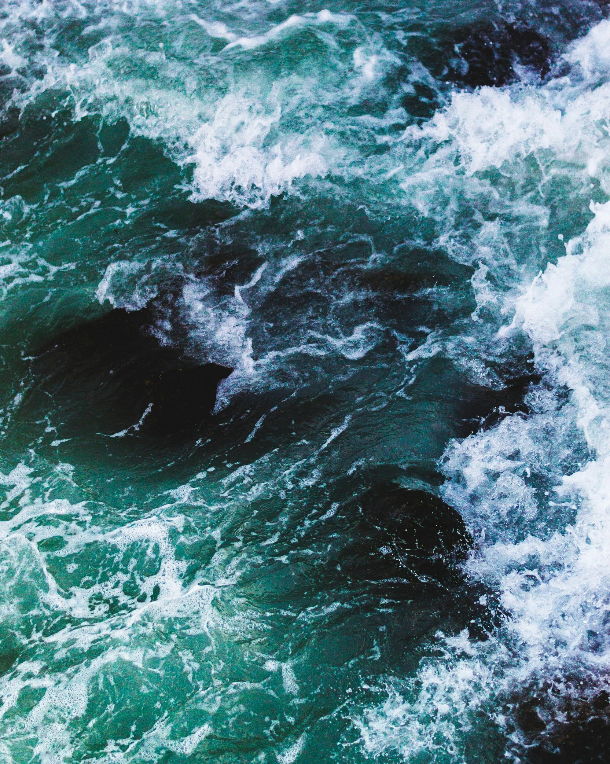 Ocean water with waves and visible rocks submerged beneath the surface.