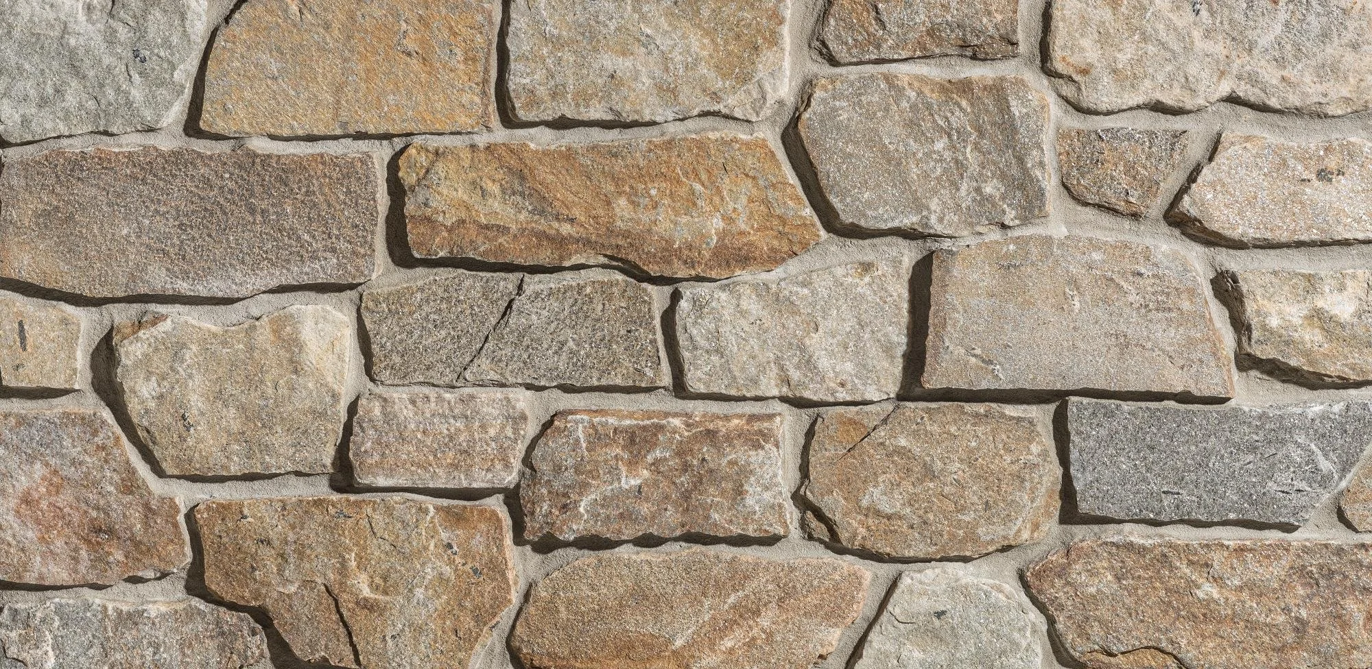Close-up view of a stone brick wall showing various sized and colored rough-hewn stones fitted together with mortar.