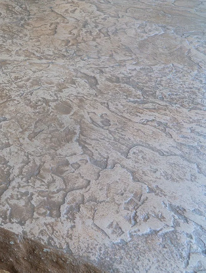 Close-up of a textured, cracked concrete or stone surface with peeling paint.