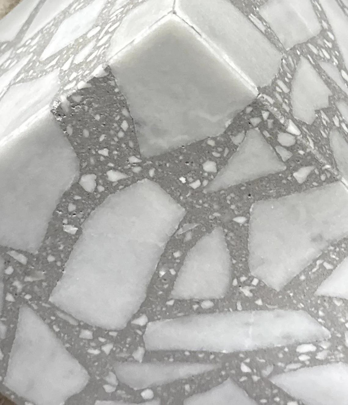 Close-up of a tiled floor with a pattern of white tiles and darker grout lines.