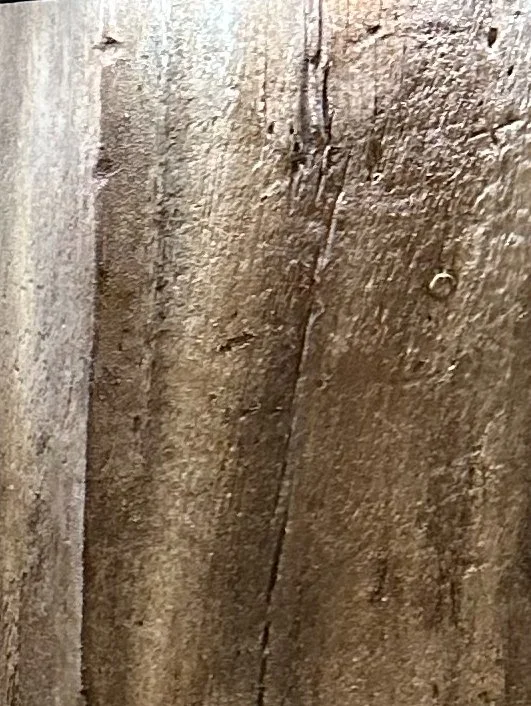 Close-up of weathered wooden surface with visible grain and cracks.