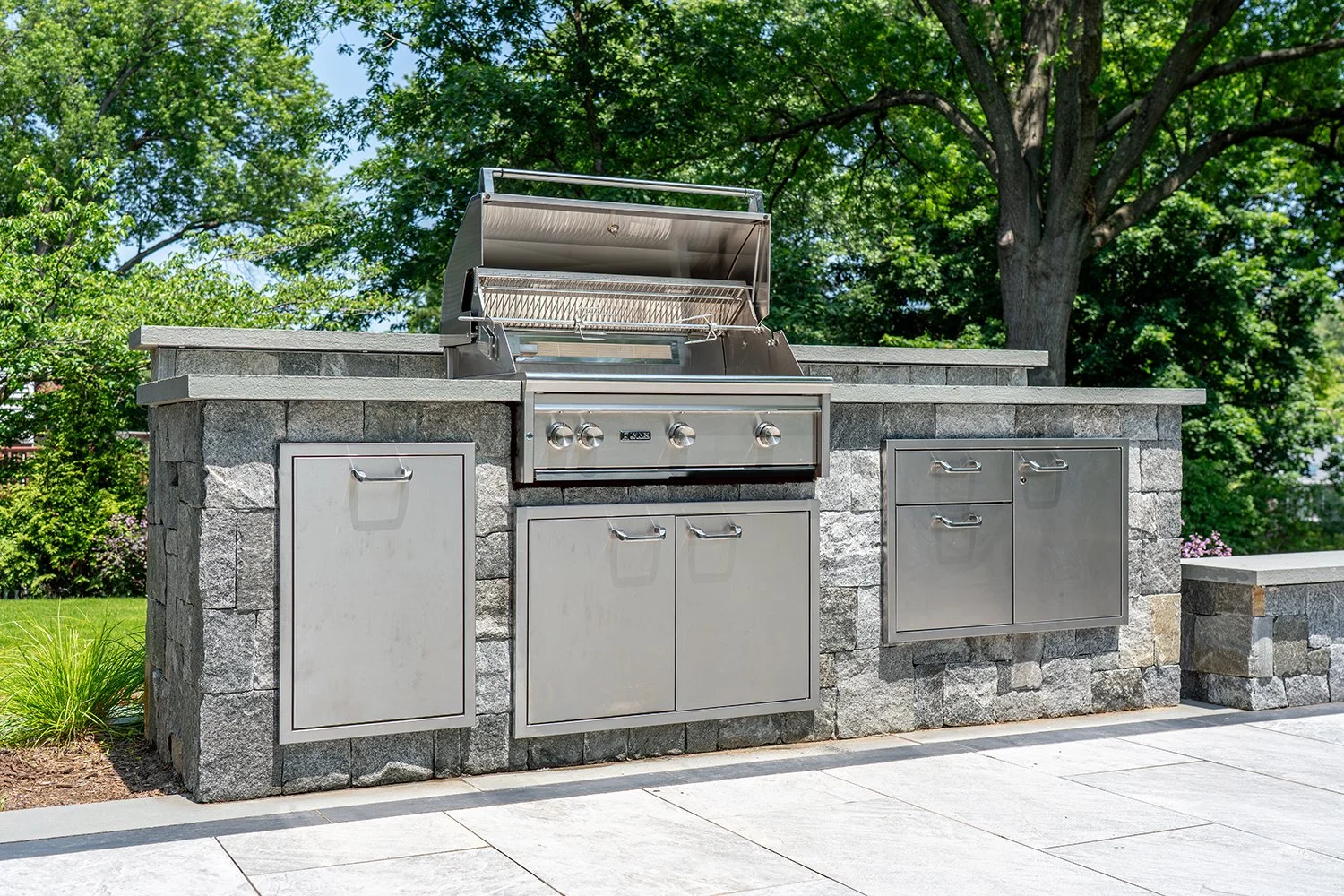 Custom built-in outdoor grill station with stainless steel appliances, stone veneer base, and integrated storage drawers. This premium BBQ island is ideal for luxury outdoor kitchens and backyard entertaining.
outdoor kitchen grill, built-in BBQ isla