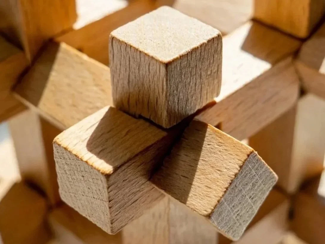 Close-up of wooden blocks arranged in a balanced structure, with three visible blocks forming a cube shape.