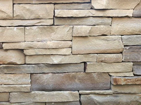 Close-up of a beige and brown stacked stone wall.