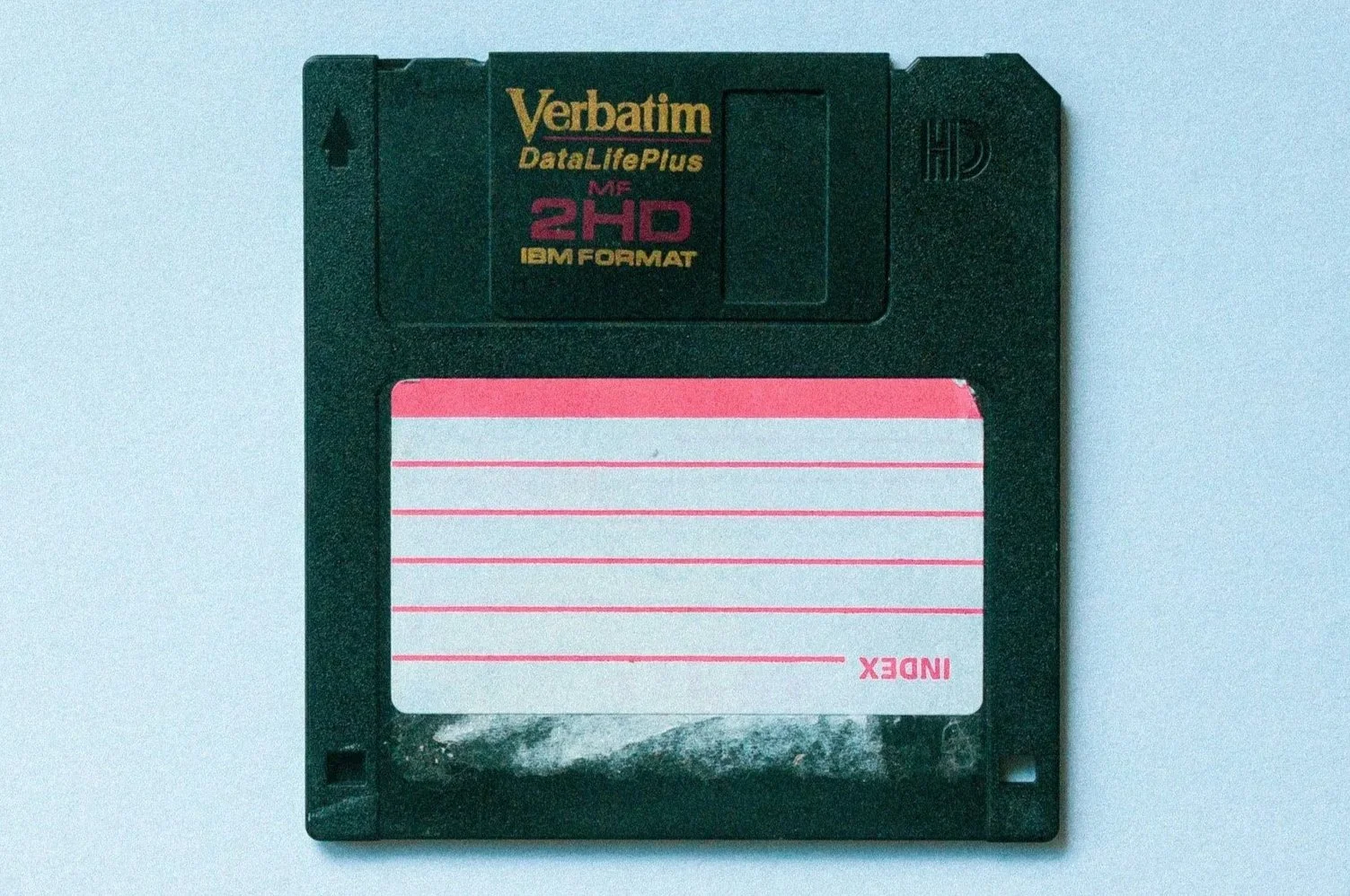 A black Verbatim DataLifePlus 2HD floppy disk with a white and pink label.