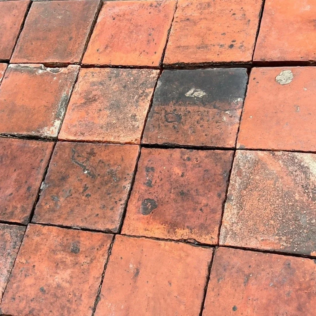 Close-up view of a patterned brick pavement with some bricks showing wear, discoloration, and mortar in between.