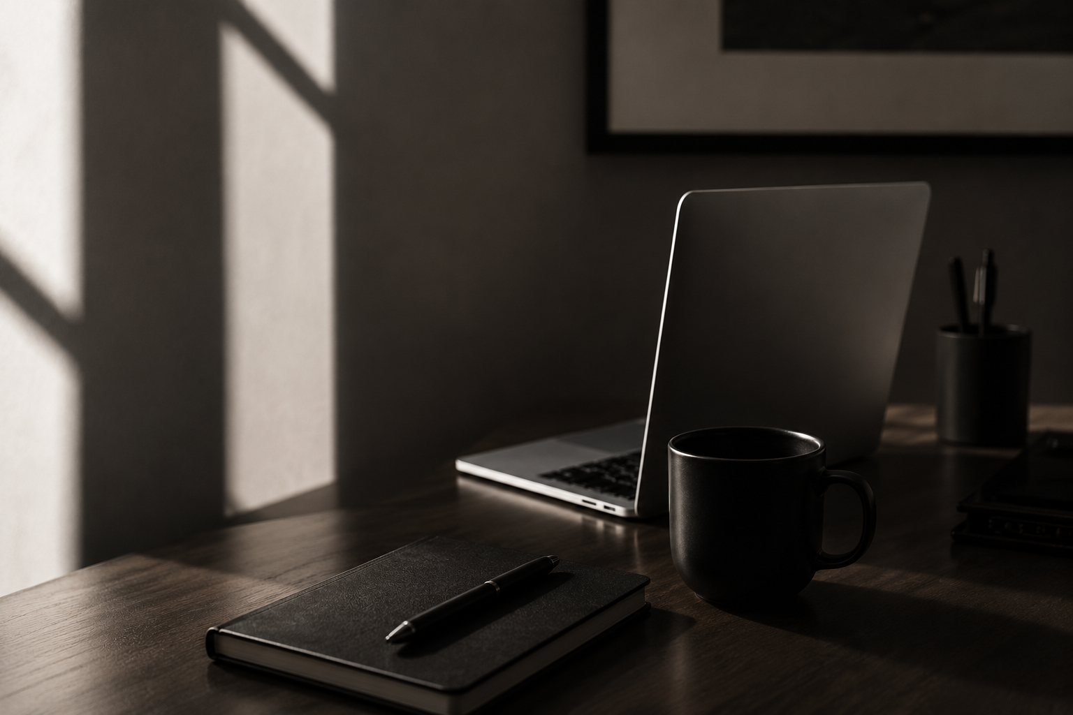 A desk that sits with a computer, cup of coffee, journal and work station.