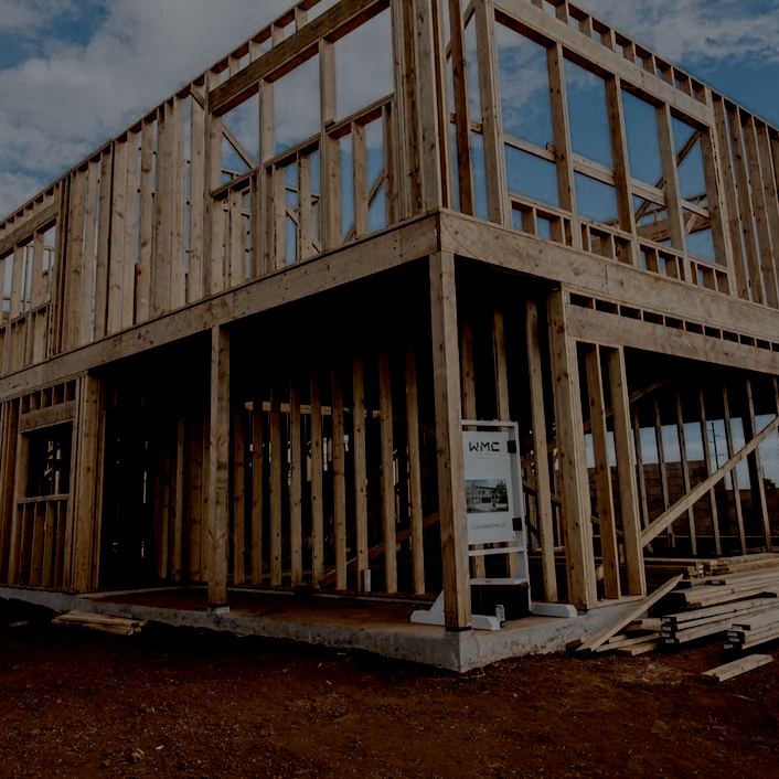 WMC Built project site with wooden framing of a two-story building under construction with a blue sky in the background.
