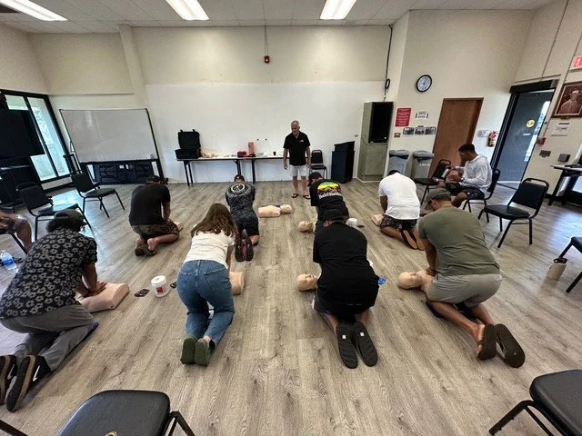 People practicing CPR on mannequins in a classroom setting for a CPR training session.