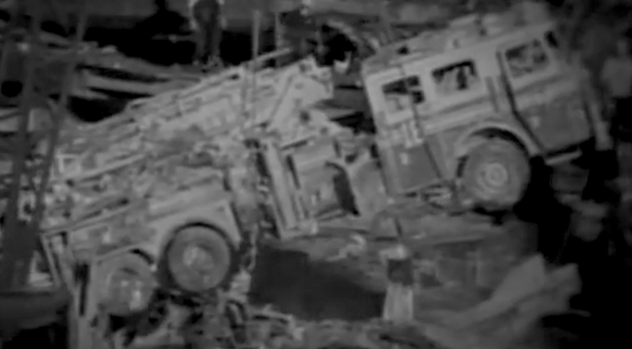 Two tall, rectangular, transparent boxes with reflective surfaces, standing side by side in a dimly lit room.