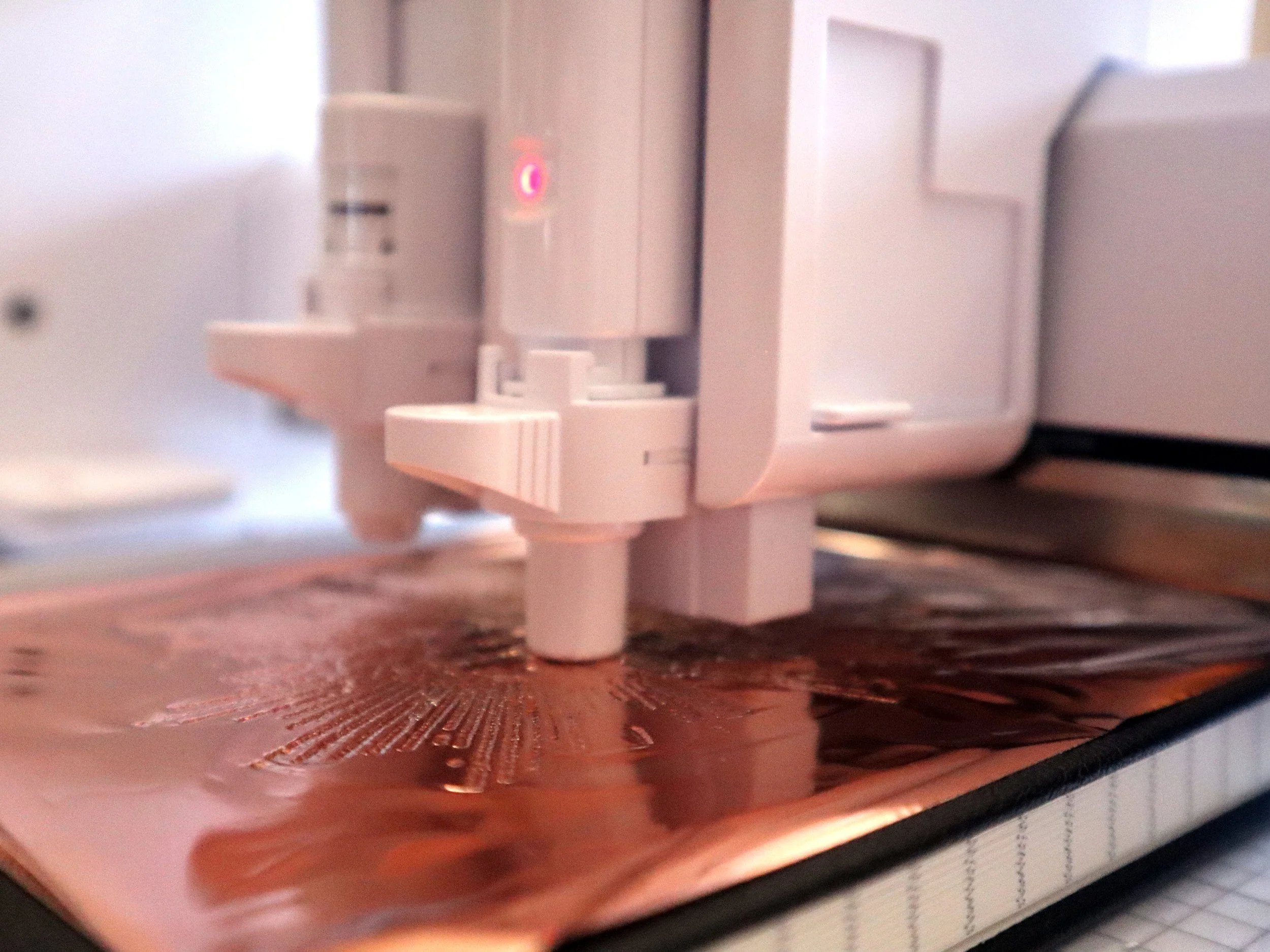 Close-up of a cutting machine embossing a Catholic notebook cover with intricate designs, showcasing the precision and craftsmanship used to create unique, faith-inspired covers.