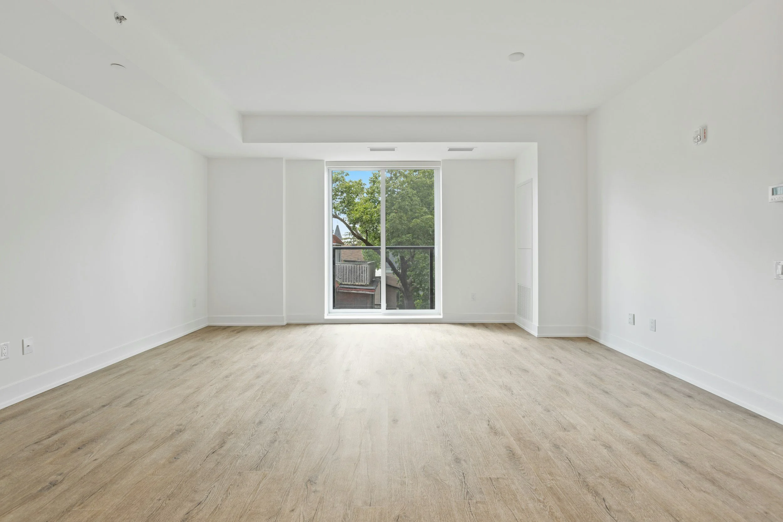 Empty bright white room with tiled floor, large window with blinds, and mirrored closet doors.