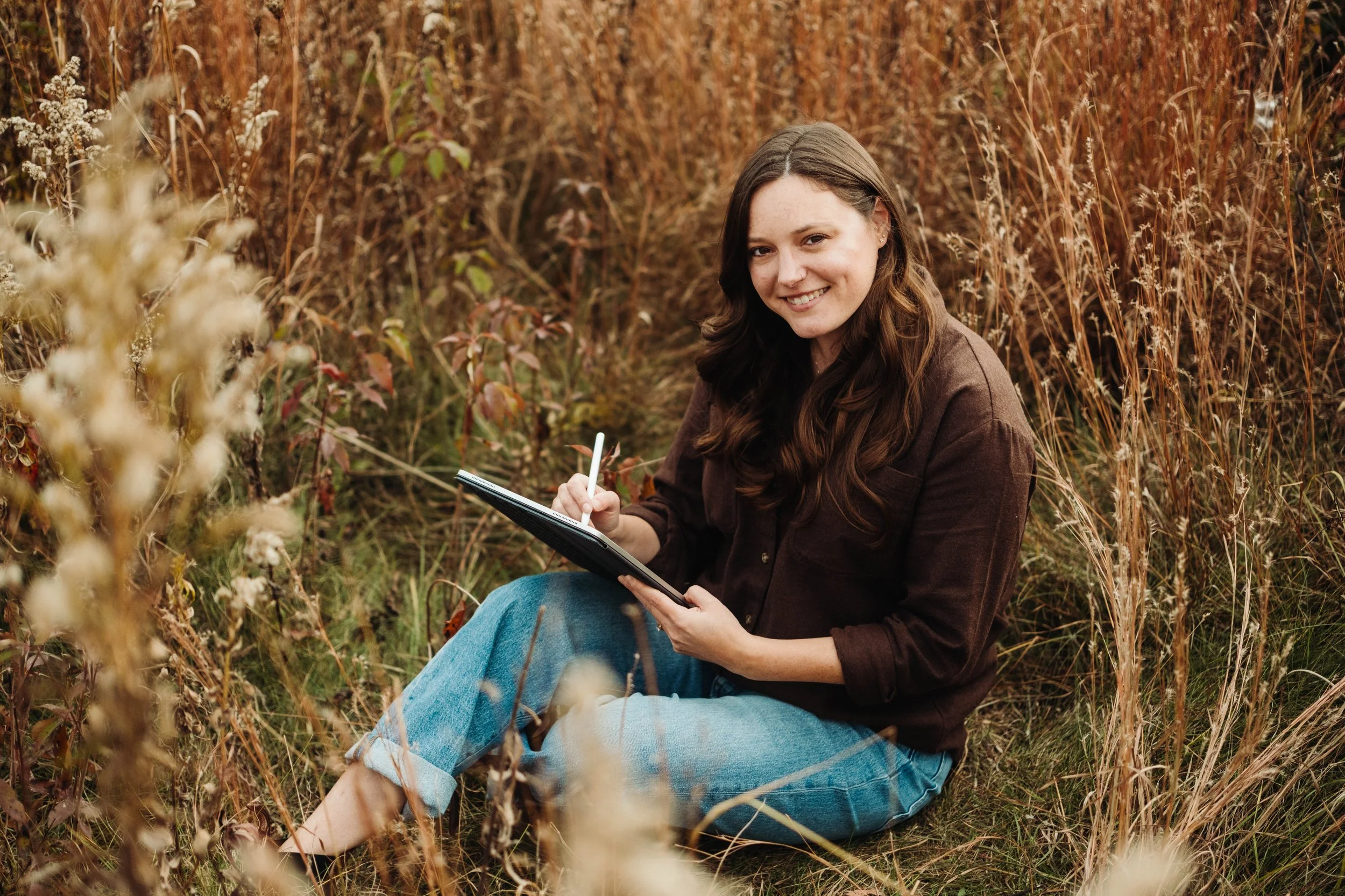 Photo of Designer and Illustrator, Kallie Goetz with ipad drawing in a field.