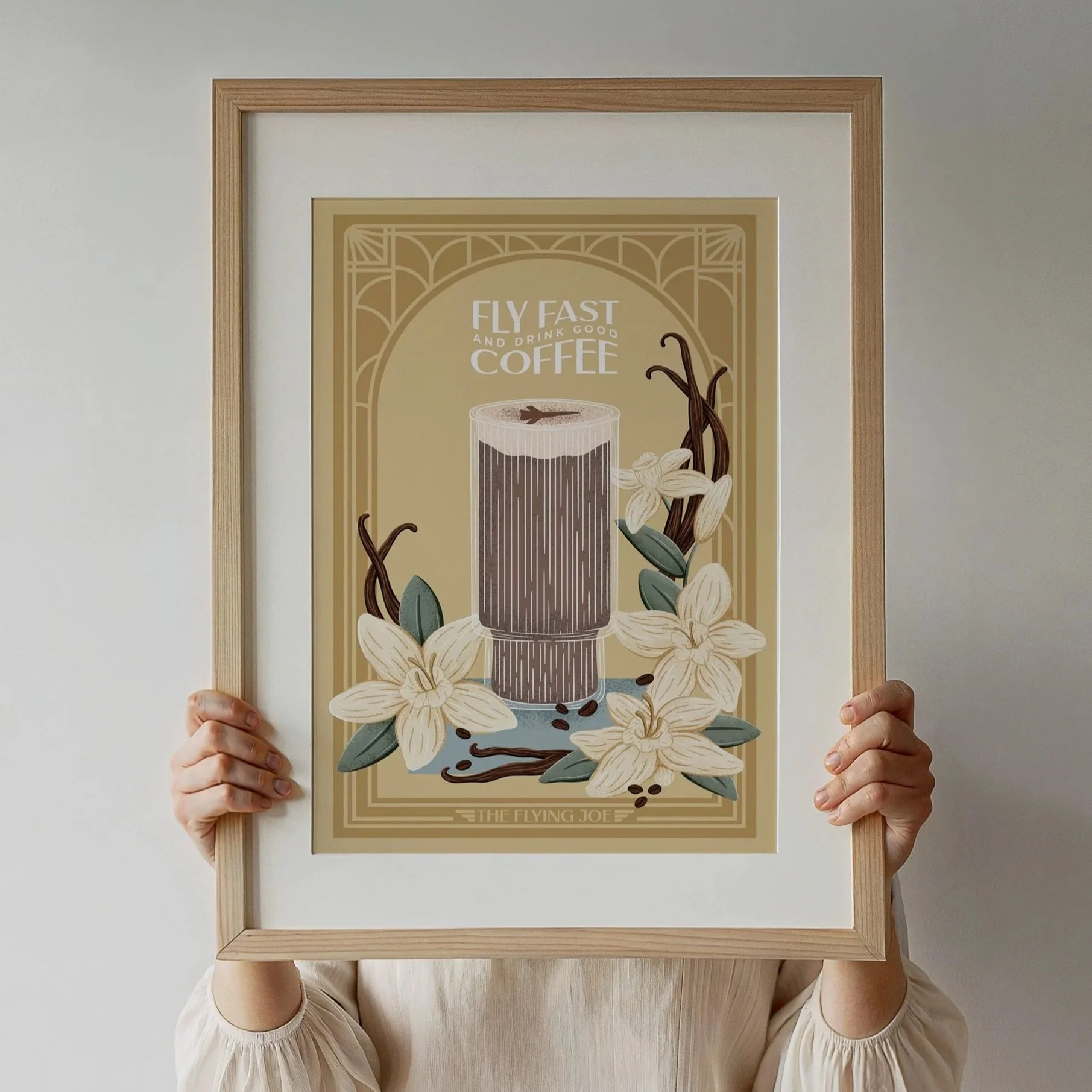 frame with poster of an iced coffee with vanilla flowers, beans, and greenery. The color of the poster is mostly gold.