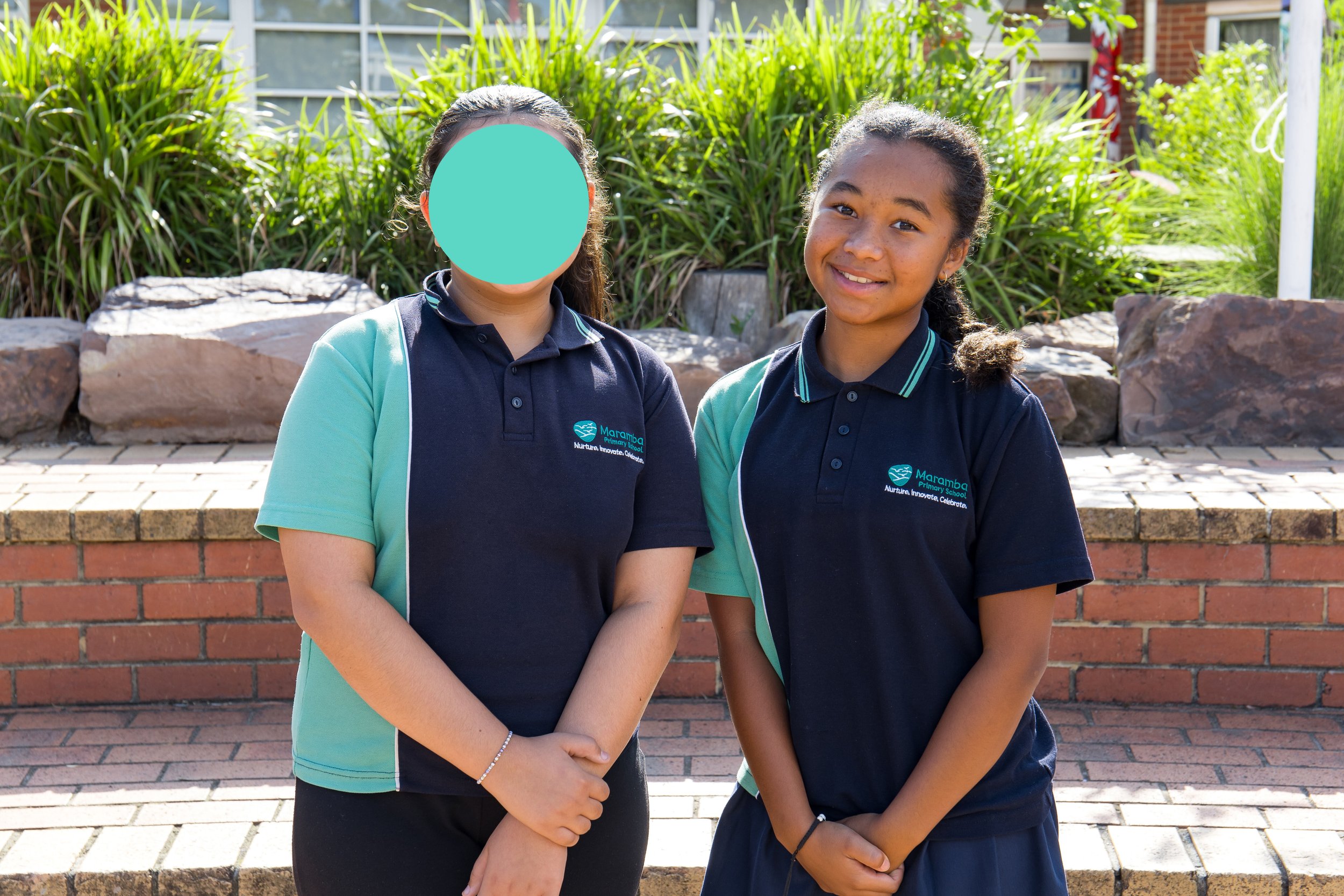 Group of young students in school uniforms posing outside, with a colorful mural featuring animals and abstract shapes in the background.