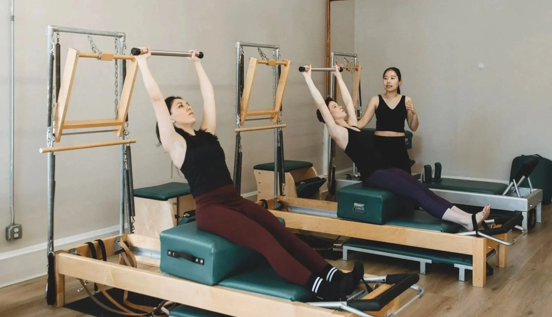 Pilates Instructor teaching 2 students in a duet session