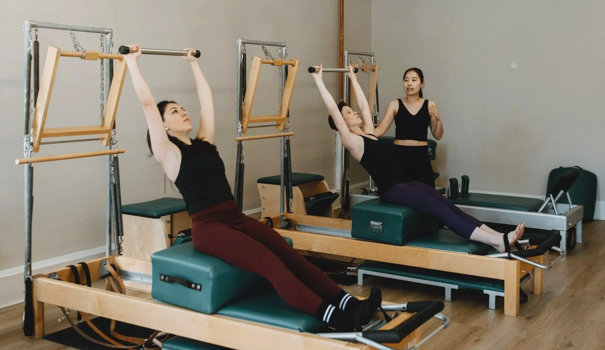 Pilates Instructor teaching 2 students in a duet session