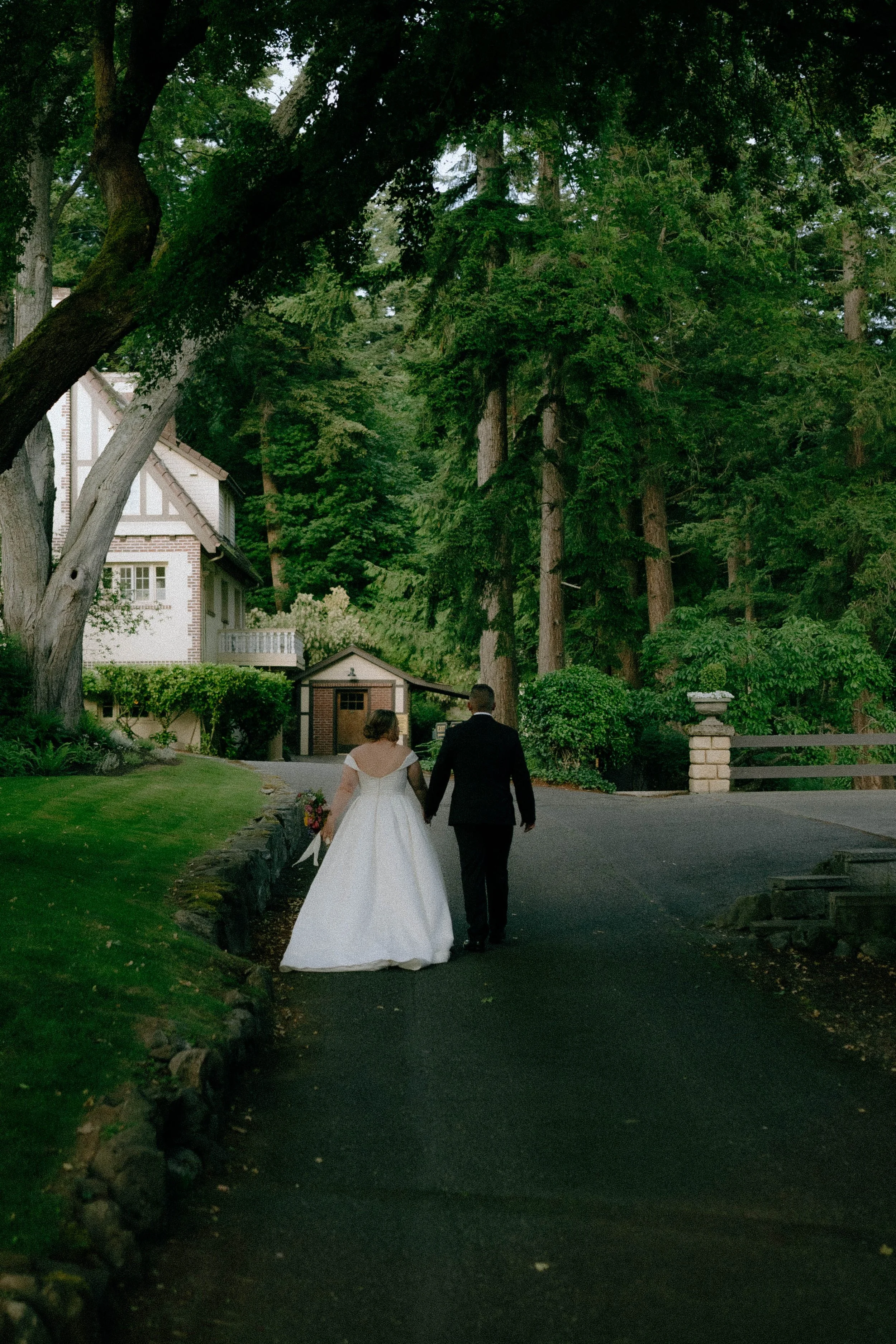 Bride and groom walk hand in hand down a tree lined path outside a grand estate - photographed by Paul Porras Photography in Albuquerque, New Mexico
